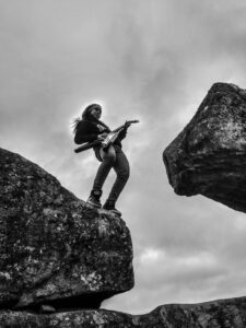 guitarspiller på klippe i uvejr