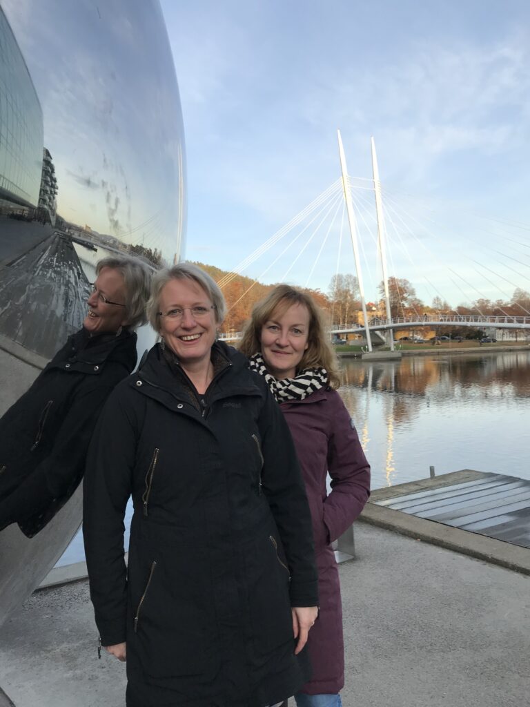 Rikke og Karin står foran skulptur, der spejler Rikke, vand og kaj.